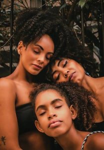 Image of 3 African American women leaning into each other and smiling. Representing 3 women who could benefit from the mental health resources and support that is offered in BIPOC therapy in North Carolina.