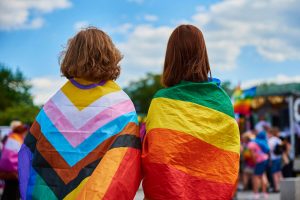 Image of 2 individuals holding pride flags around their shoulders. Showing that anyone can come to LGBTQIA therapy in North Carolina. You can find a safe place to grow with a LGBTQ friendly therapist in Chapel Hill, NC through online LGBT therapy or gender therapy in North Carolina.