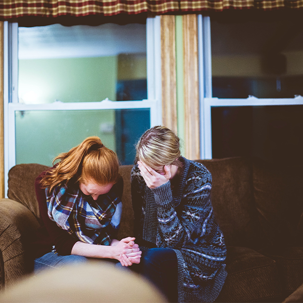 Image of 2 people sitting together and crying. Representing what loss can look like but a grief counselor in North Carolina can help. In grief counseling, or online therapy for grief, you can find a safe space to let your emotions flow.