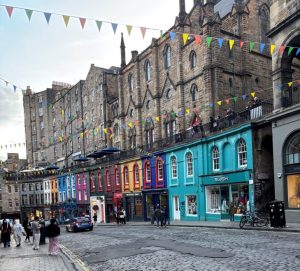 Victoria Street in Edinburgh with rainbow-colored shopfronts – lively yet grounding travel scene for PTSD travel tips.